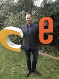 Man in Formal Attire Stands Next to C Sign