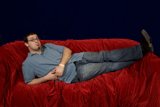 Man lounging on red velvet couch
