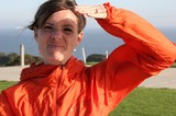 Woman in Orange Jacket Saluting by the Coast