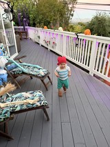 Joyful Toddler in Pink Hat Running on Decorated Deck