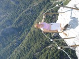 Fearless Woman Perches on Cliff Edge Over Mountain Abyss
