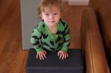 Toddler in Green Bat Pajamas on Ottoman