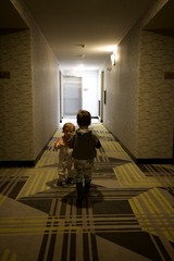 Two Children Walking Down Hotel Corridor at Dusk