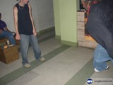 Black-Shirted Man Walking Barefoot on Plywood Flooring