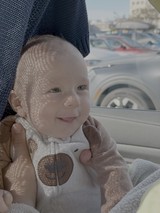 Smiling Baby in Car Seat with Dappled Sunlight