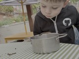 Young Boy Gazing into Cooking Pot Outdoors
