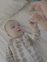Newborn Baby Reaching Hand Up on Bed