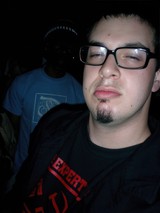 Dave B poses in black shirt and glasses