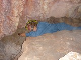 Caver Navigates Tight Underground Passage with Flashlight