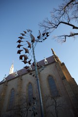 Metal Phoenix Sculpture Against Historic Church at Dusk