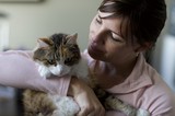 Woman Tenderly Holds Her Calico Cat Indoors