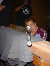 Woman Aiming Rifle Through Scope Indoors