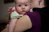 Wide-Eyed Baby Resting on Mother's Shoulder