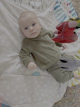 Baby in Green Outfit Lying on Bed
