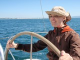 Woman Confidently Steering Sailboat on Open Water