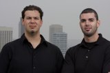 Two Happy Men Pose in Front of Skyscraper