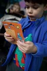 Young Boy Reading Orange Toy Package Intently