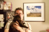 Man Holds Dark Cat Up to His Face