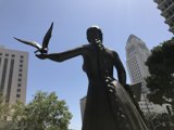 Woman and Bird Statue against the Urban Skyline