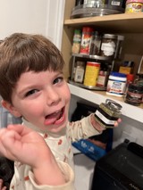 Young Boy Excitedly Tasting Food in Kitchen
