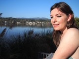Woman Smiling by a Tranquil Lakeside on Sunny Day