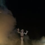 Man in White Suit Dancing in Front of a Fire
