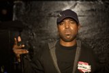 Steve J holding a microphone in a black hat and jacket