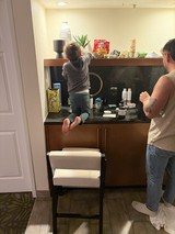Young Child Climbing Kitchen Counter with Parent Supervising