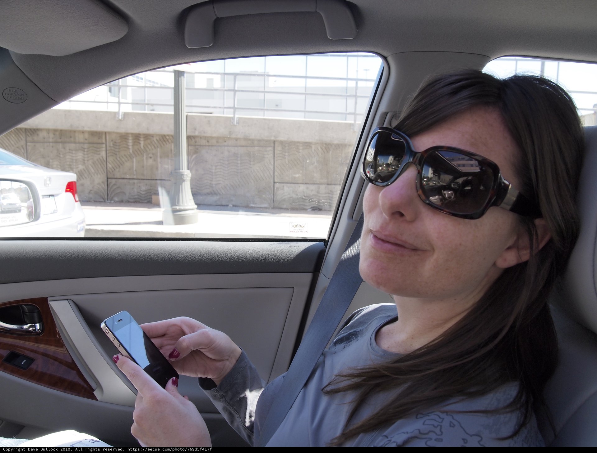 Woman Texting on Smartphone in Urban Car Ride