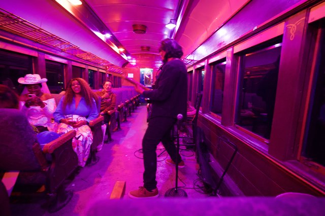 Live Music Performance in Vibrant Purple-Lit Train Car