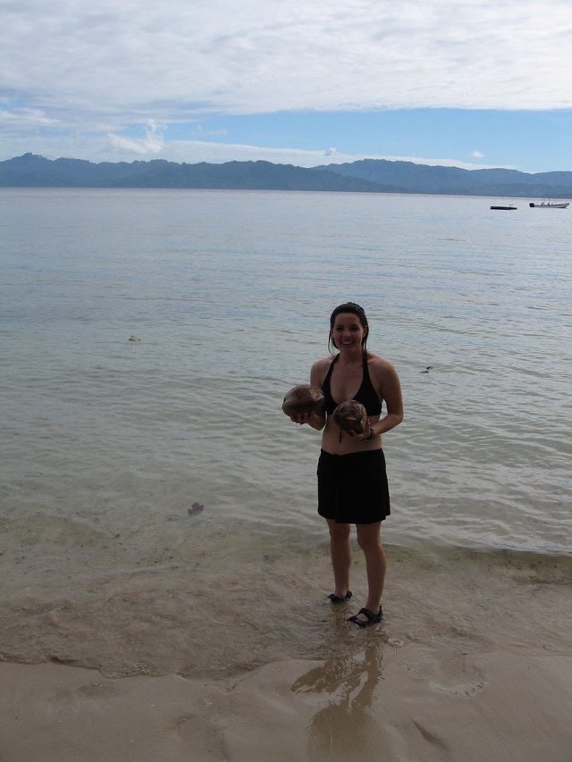 Smiling Woman Holds Coconuts on Fijian Beach
