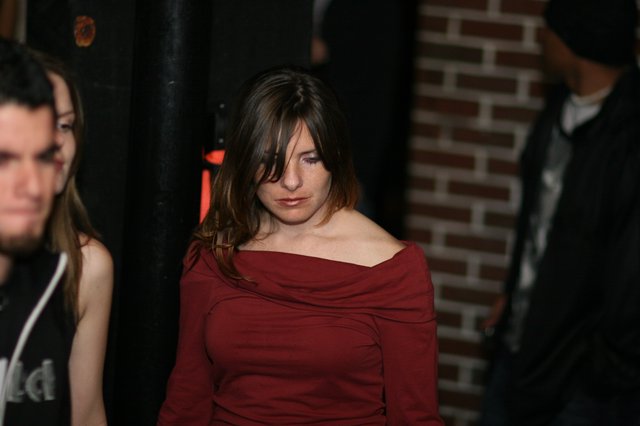 Contemplative Woman in Red at Dimly Lit Venue