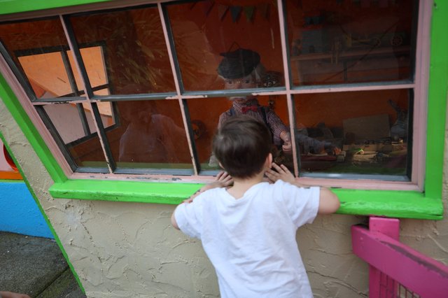 Child Peering into Window of Colorful Playhouse