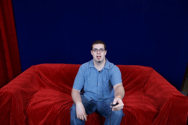 Dave B lounges on a red velvet sofa