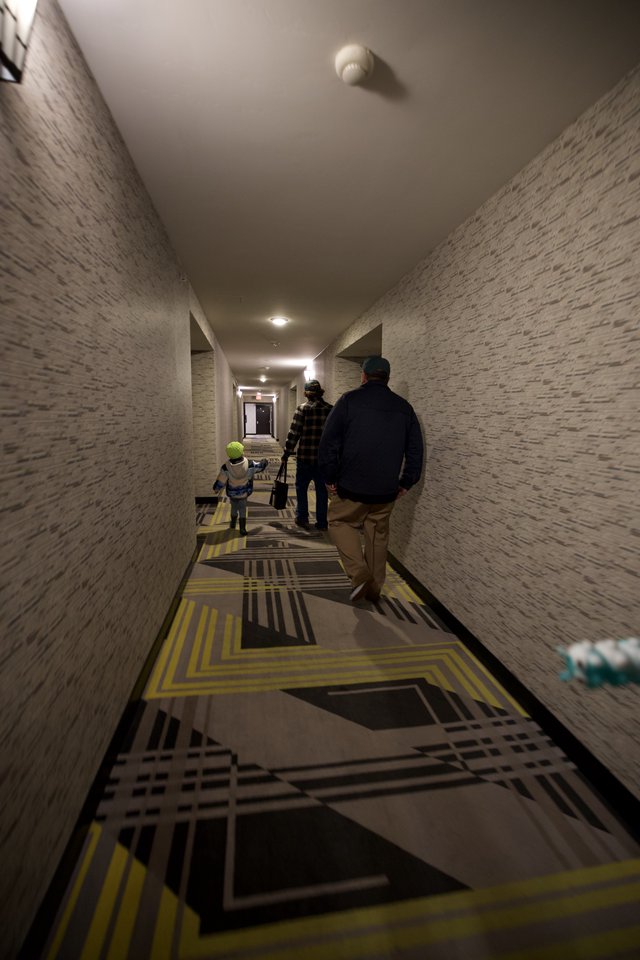 Family Walking Down Modern Hotel Corridor with Geometric Carpet