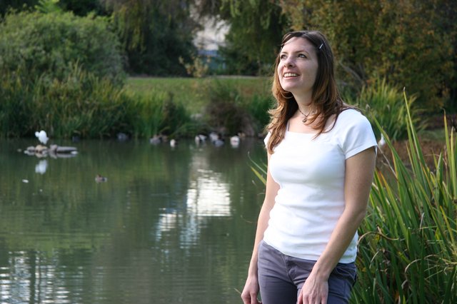 Woman Gazing Skyward by a Tranquil Park Pond