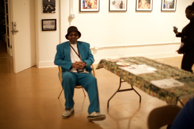 Blue Suited Man Sitting on Hardwood Chair in Art Gallery