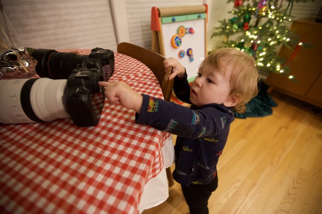 Young Child Exploring Professional Camera Equipment at Christmas