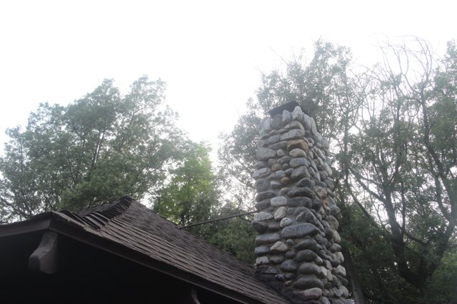 Slate-roofed stone chimney in rural setting