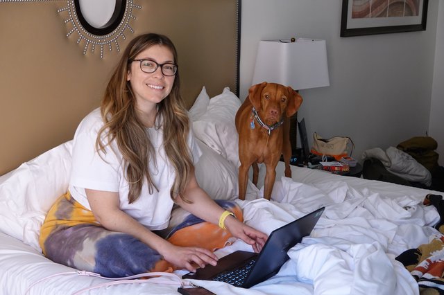 Woman and Dog Working from Bed