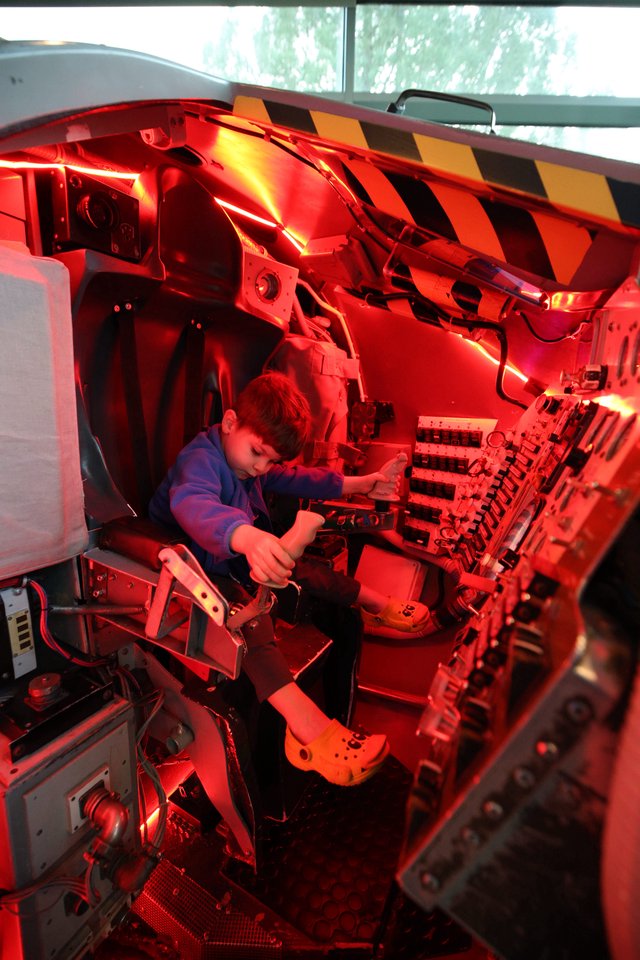 Young Visitor Explores Space Shuttle Cockpit Simulator