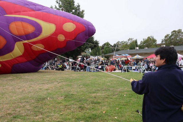 Ground Crew Tethers Colorful Hot Air Balloon at Festival