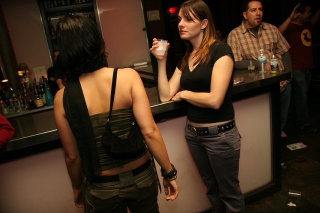 Two Women Conversing at a Dimly Lit Bar