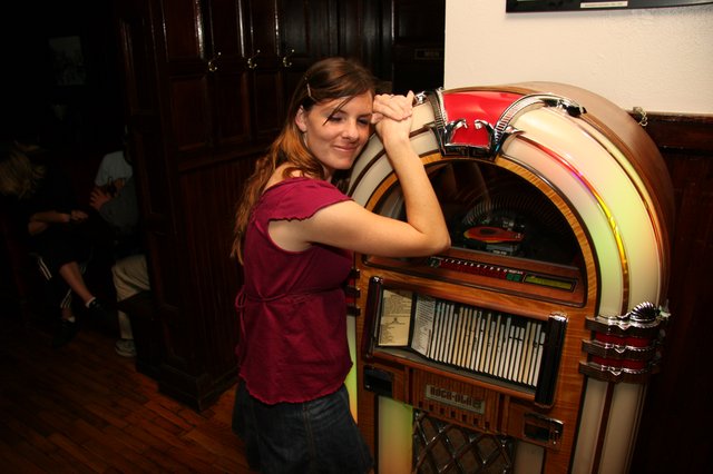 Young Woman Poses Playfully with Classic Jukebox