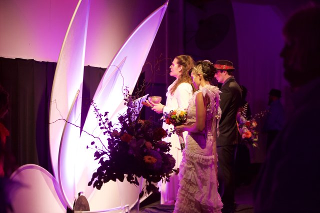 Elegant Wedding Couple Poses Next to Luxurious Flower Arrangement