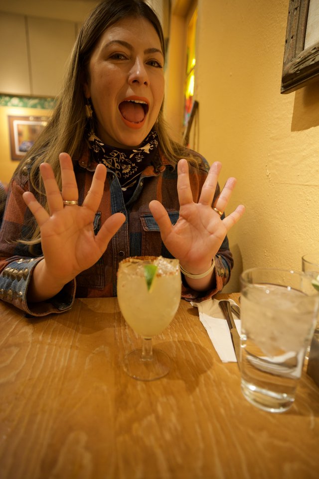 Enthusiastic Woman Celebrating with Margarita at Restaurant
