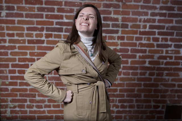Playful Woman Strikes Pose Against Urban Brick Wall
