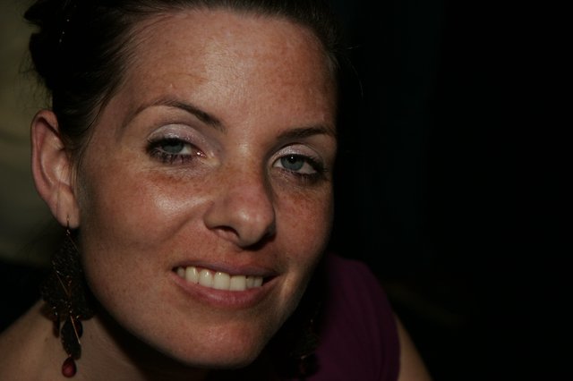 Freckled Woman with Blue Eyes Smiling in Dark Setting