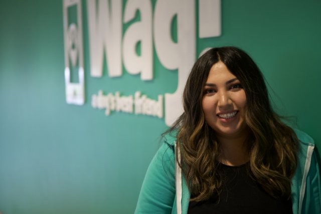 Smiling Woman Poses in front of WAG Logo