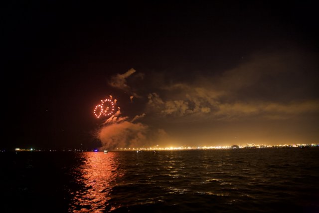 Bursting Fireworks over the Glittering Ocean